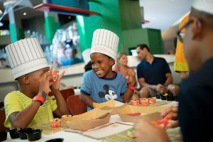 Two young boys at the table wearing chef hats and playing with sushi at Epcot International Food and Wine Festival in Orlando