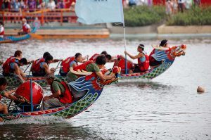 Two dragon boats racing, neck and neck with each other