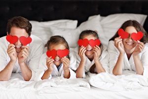 Family at hotel holding red valentine hearts over their eyes