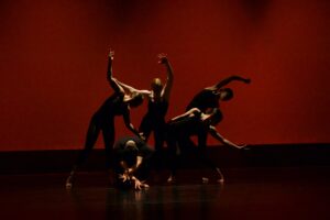 UCF Celebrates the Arts - dancers posting on stage against a red backdrop.