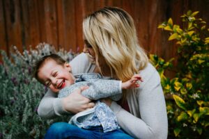 Mother' Day Buffet - a mom plays with her young, laughing child in a garden.